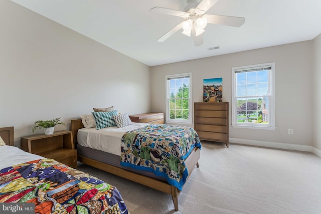bedroom with a ceiling fan, visible vents, light colored carpet, and baseboards