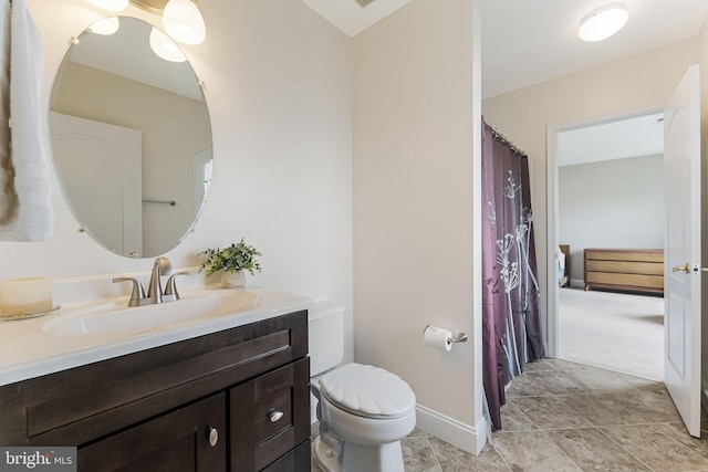 bathroom featuring baseboards, toilet, and vanity