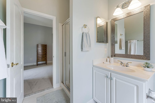 bathroom with tile patterned floors, vanity, a shower stall, and baseboards
