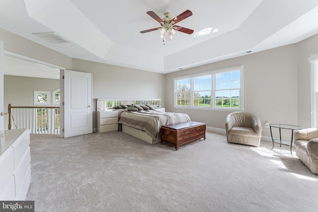 bedroom featuring a raised ceiling, visible vents, a ceiling fan, and light carpet