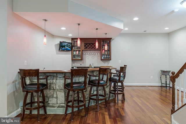 bar with dark wood-style flooring, recessed lighting, wet bar, and stairs
