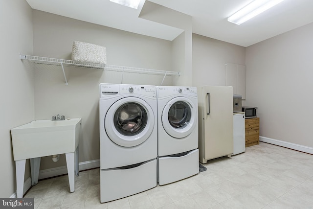 clothes washing area with independent washer and dryer, laundry area, and baseboards