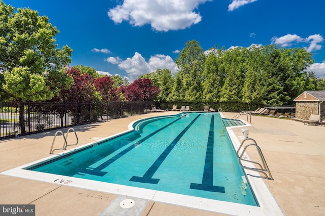 community pool with a patio area and fence