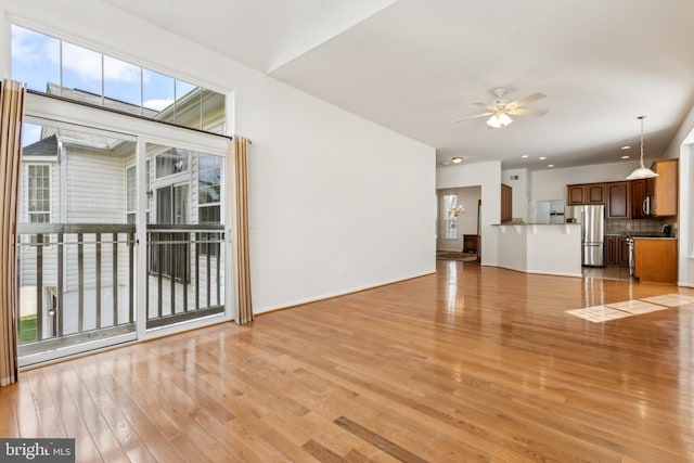unfurnished living room featuring light wood-style floors, baseboards, and a ceiling fan