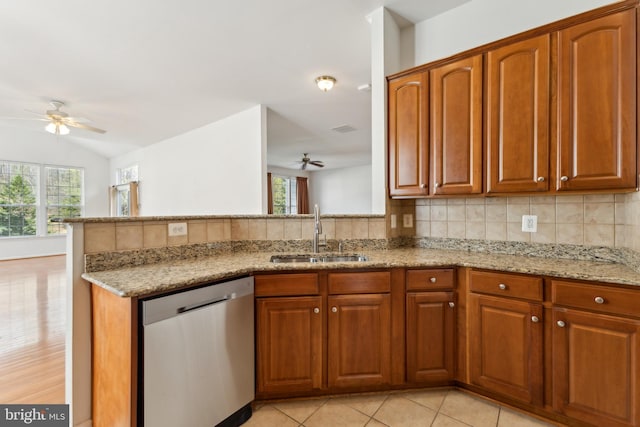 kitchen featuring a sink, stainless steel dishwasher, a ceiling fan, and light stone countertops