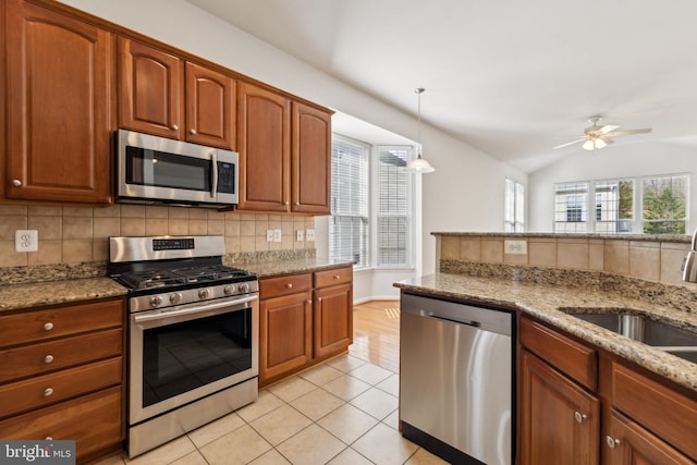 kitchen featuring a ceiling fan, appliances with stainless steel finishes, light stone counters, and backsplash
