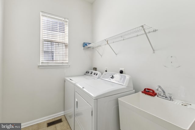 clothes washing area with laundry area, visible vents, washing machine and clothes dryer, a sink, and baseboards