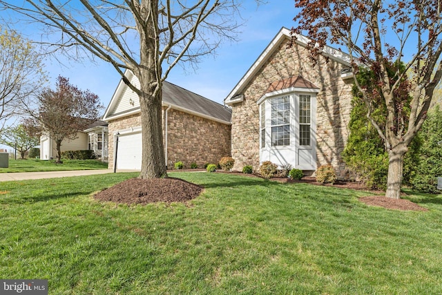 ranch-style home featuring an attached garage, driveway, a front yard, and stone siding
