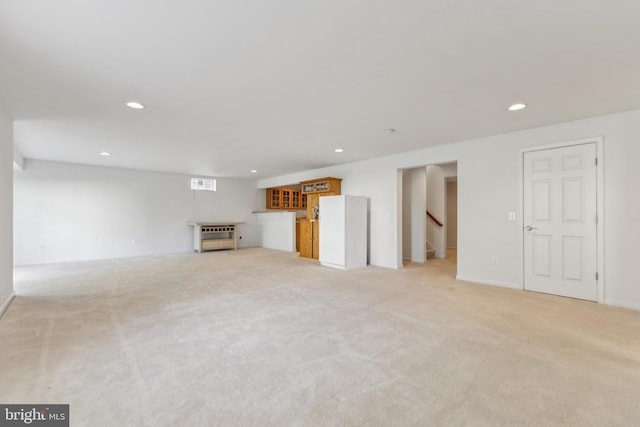 unfurnished living room featuring recessed lighting, light colored carpet, and stairs