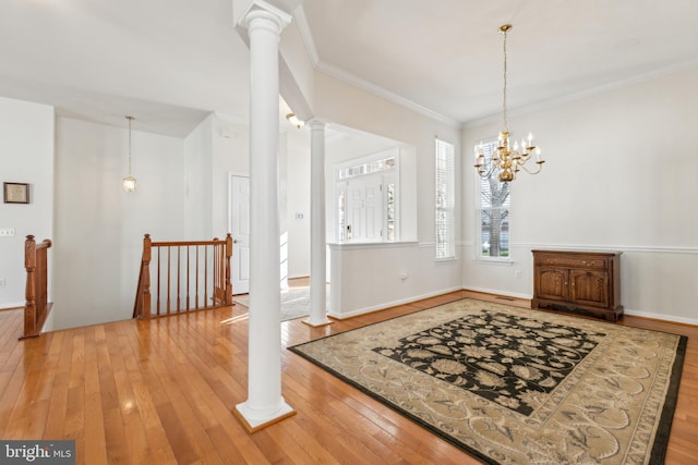 entryway featuring a chandelier, hardwood / wood-style floors, decorative columns, and crown molding