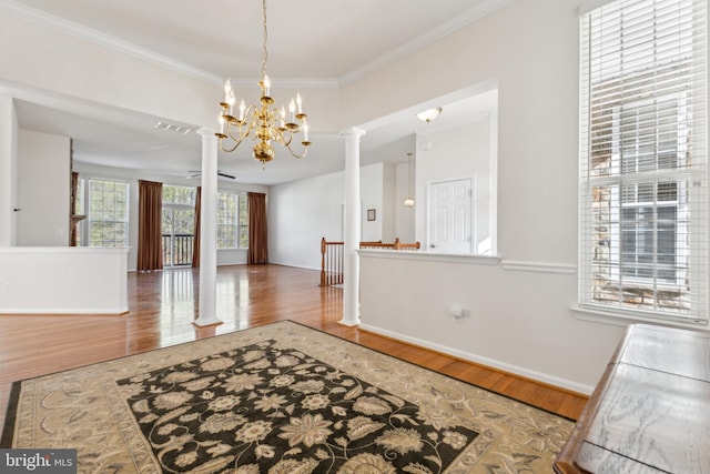 unfurnished dining area with an inviting chandelier, crown molding, visible vents, ornate columns, and wood finished floors