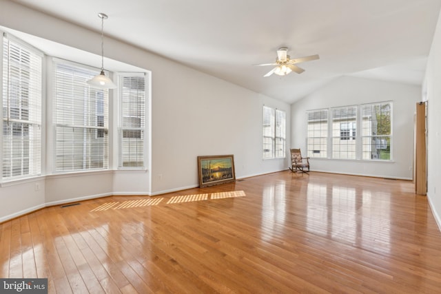 unfurnished living room featuring a ceiling fan, vaulted ceiling, visible vents, hardwood / wood-style floors, and baseboards