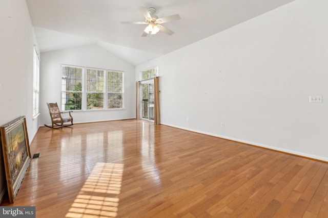 interior space featuring light wood-style floors, baseboards, a ceiling fan, and vaulted ceiling