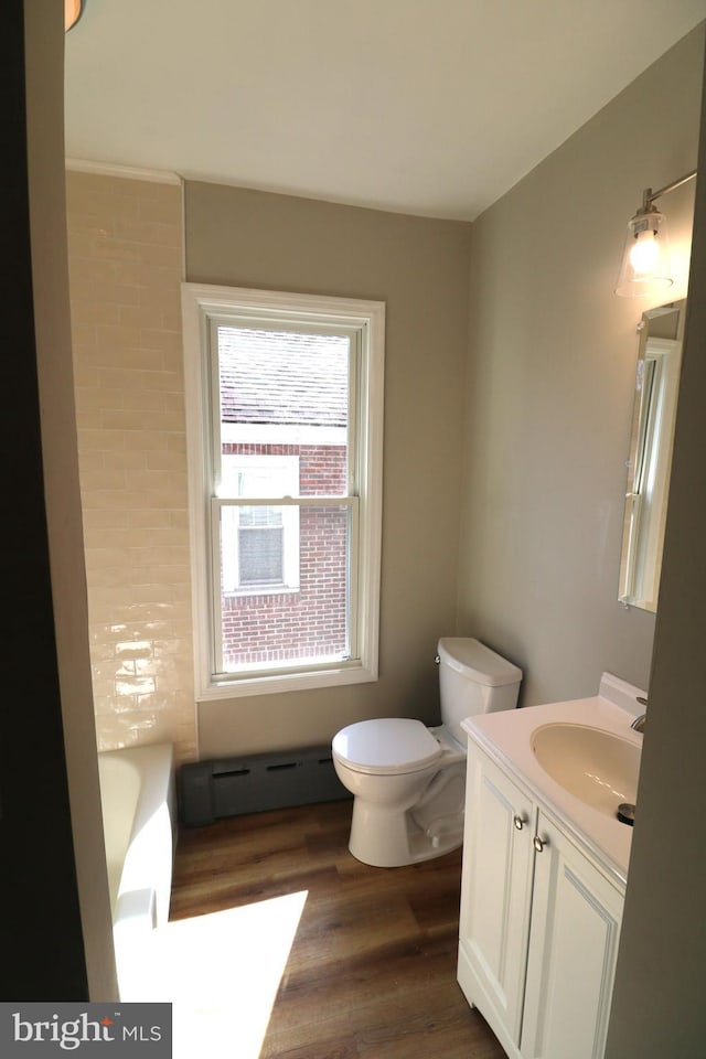 bathroom with toilet, vanity, a tub, wood finished floors, and a baseboard radiator
