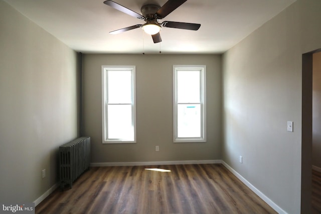 empty room featuring radiator heating unit, a ceiling fan, dark wood-type flooring, and baseboards