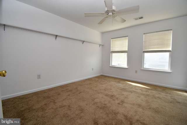carpeted spare room with a ceiling fan and baseboards