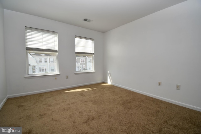 carpeted empty room featuring baseboards