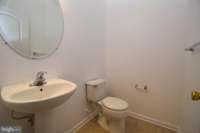 bathroom featuring tile patterned flooring, baseboards, and toilet