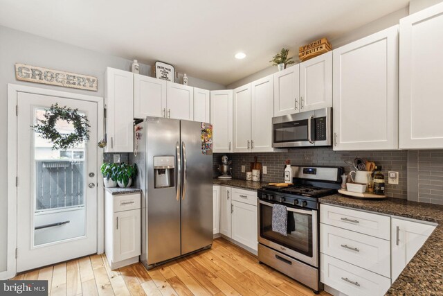2512 Collins St, Philadelphia, PA 19125 - kitchen featuring tasteful backsplash, dark stone countertops, light wood-type flooring, white cabinetry, and appliances with stainless steel finishes