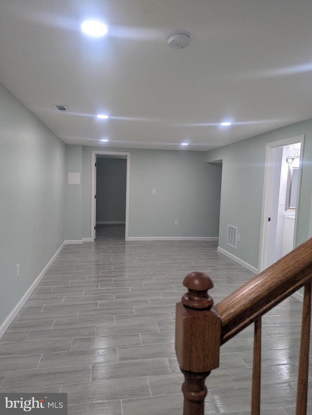 finished below grade area featuring baseboards, visible vents, and light wood-style flooring