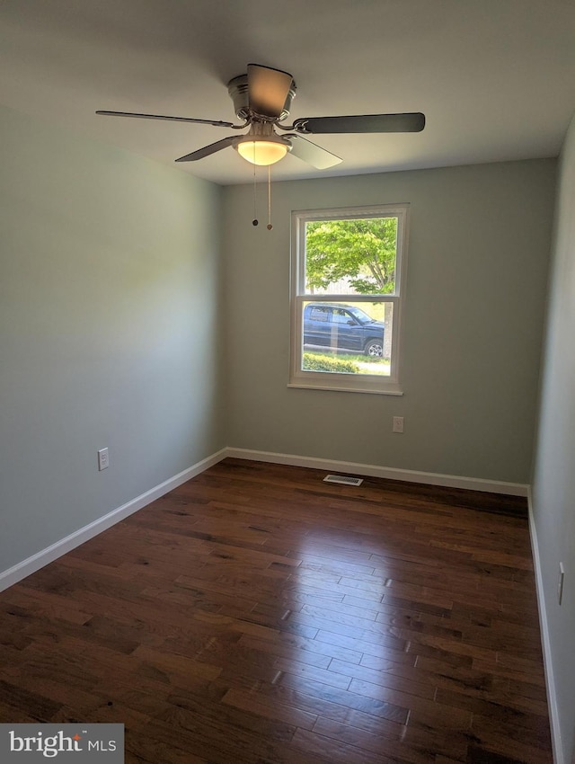 unfurnished room with dark wood finished floors, visible vents, baseboards, and ceiling fan