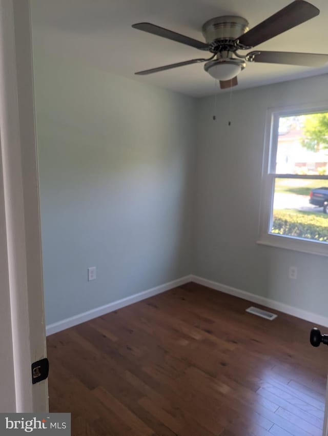 spare room featuring wood finished floors, visible vents, baseboards, and ceiling fan