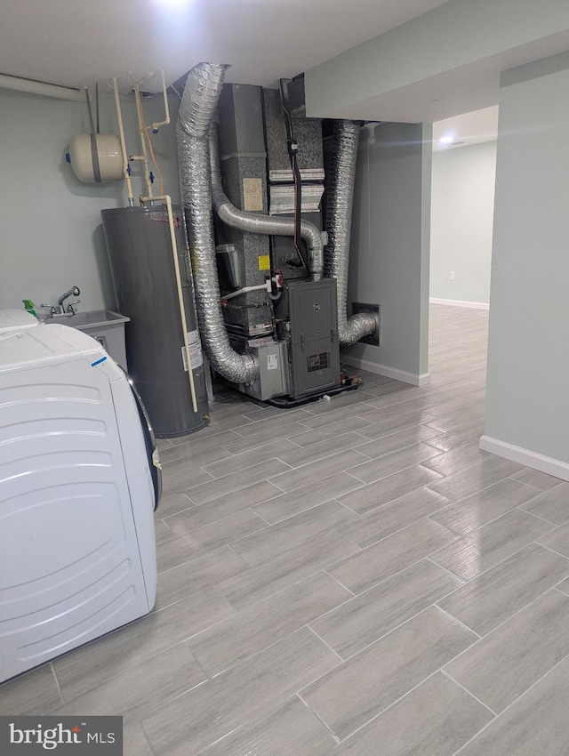utility room with water heater, washer / dryer, heating unit, and a sink