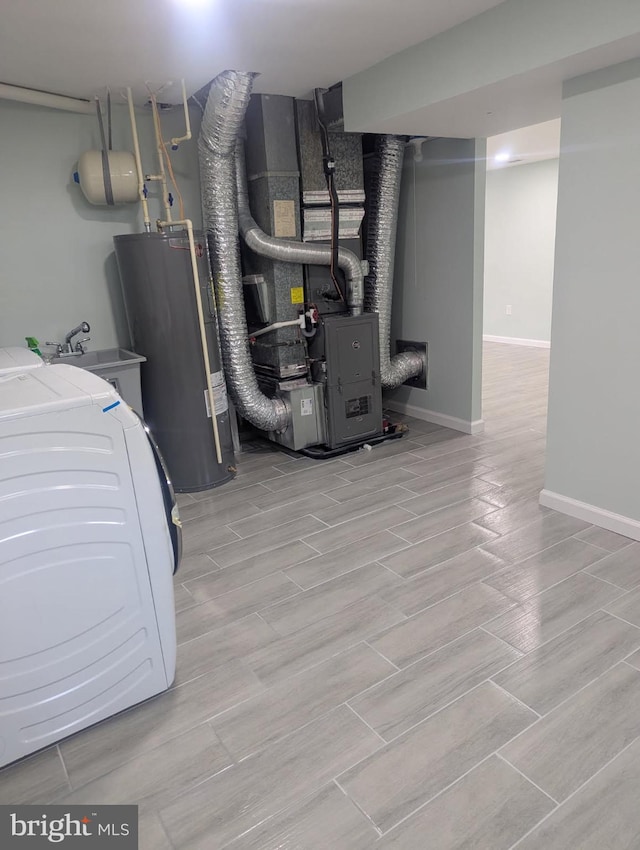 utility room with heating unit, electric water heater, and a sink