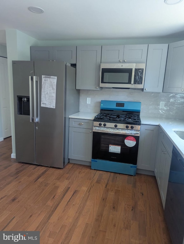 kitchen featuring stainless steel appliances, light wood-style flooring, light countertops, and tasteful backsplash