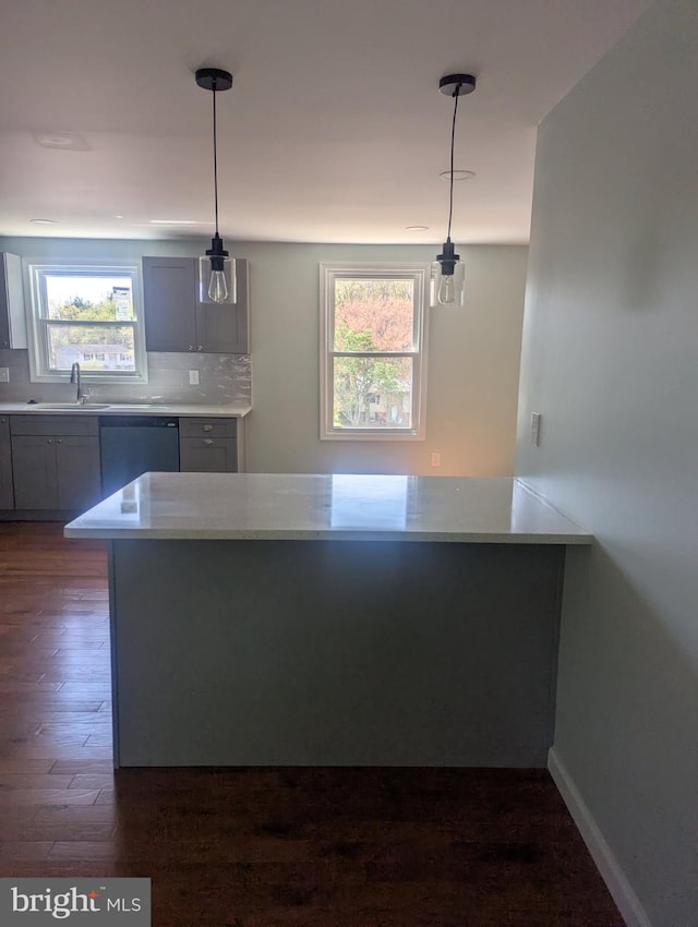 kitchen featuring light countertops, dishwasher, dark wood-style floors, and a sink