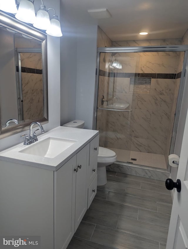full bathroom featuring a shower stall, toilet, and vanity