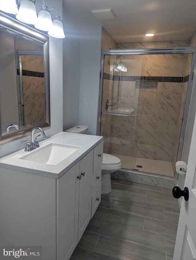 full bath featuring a stall shower, vanity, and toilet