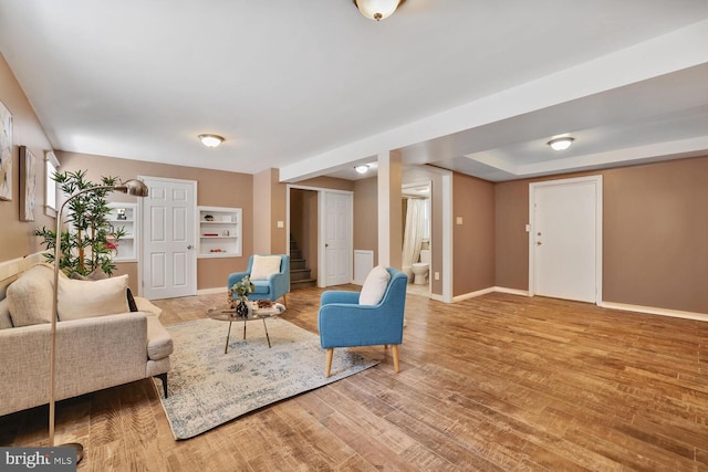 living area featuring baseboards, wood finished floors, and stairway