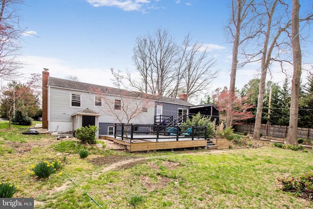 rear view of house with fence, a chimney, a lawn, and a deck