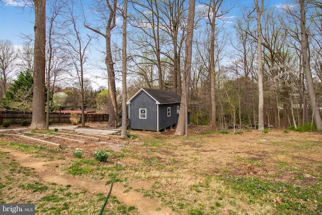 view of yard featuring fence, a storage unit, and an outdoor structure