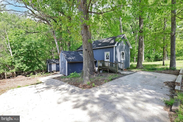 view of front of property featuring a wooden deck, an outdoor structure, and roof with shingles