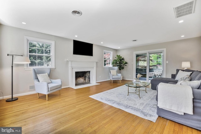 living area with visible vents, a fireplace with flush hearth, light wood-style flooring, and recessed lighting