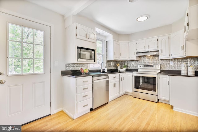 kitchen featuring a sink, dark countertops, stainless steel appliances, and under cabinet range hood