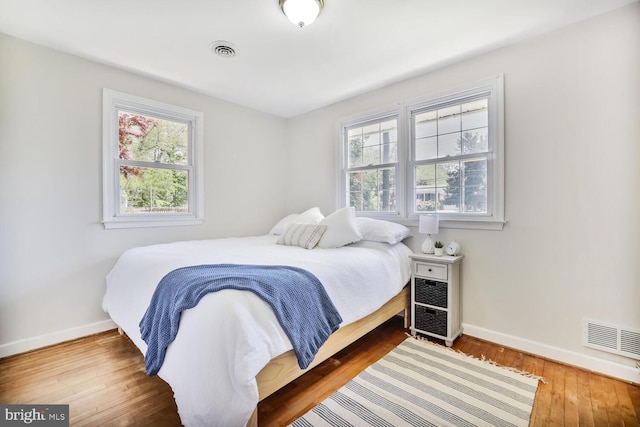 bedroom with baseboards, wood-type flooring, and visible vents