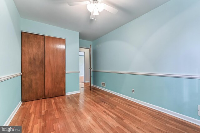 unfurnished bedroom featuring visible vents, baseboards, wood finished floors, a closet, and ceiling fan