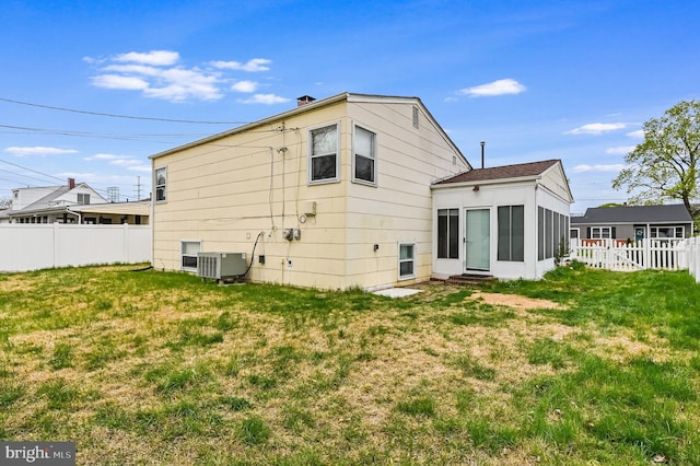 rear view of property featuring a yard, a fenced backyard, central AC, and a sunroom
