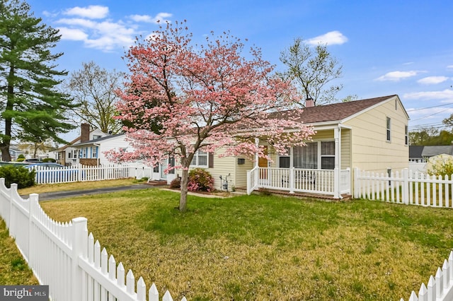 view of front of house featuring a fenced backyard, a chimney, and a front lawn