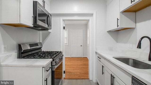 5011 37th Ave, Hyattsville, MD 20782 - kitchen with light wood-type flooring, a sink, white cabinetry, and stainless steel appliances