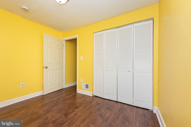 unfurnished bedroom featuring baseboards, a closet, and dark wood-type flooring