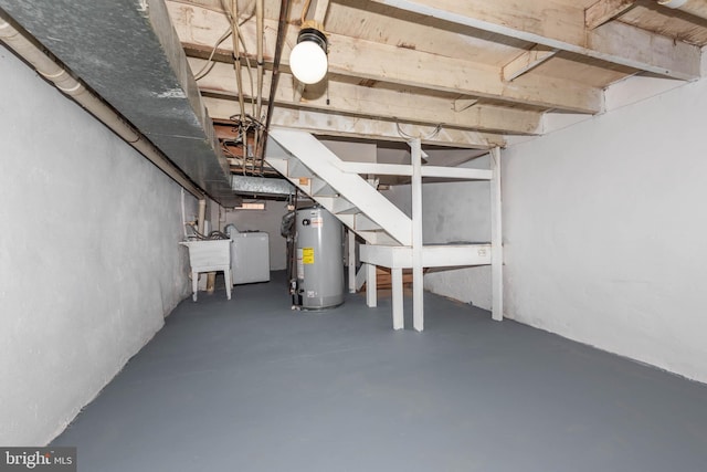 unfinished basement with water heater, a sink, stairway, and washer / dryer