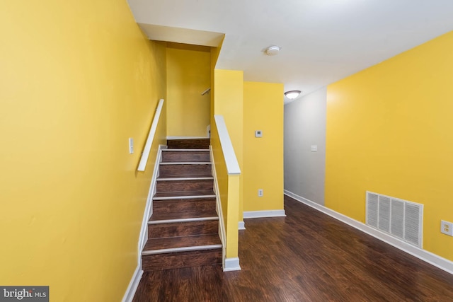 stairway featuring baseboards, visible vents, and wood finished floors