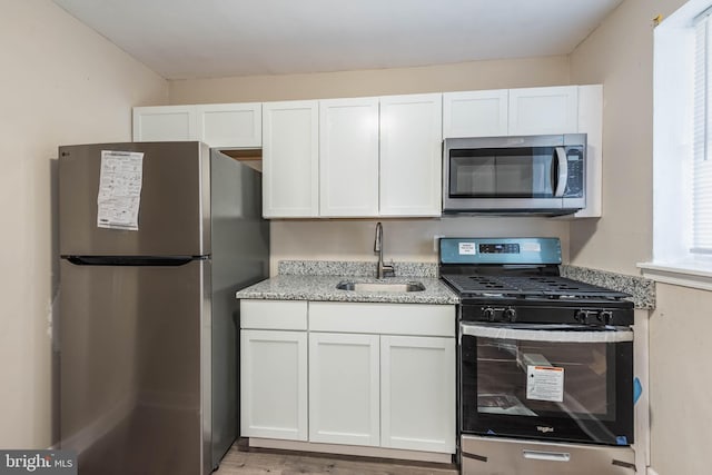 kitchen featuring white cabinetry, a sink, light stone countertops, and appliances with stainless steel finishes