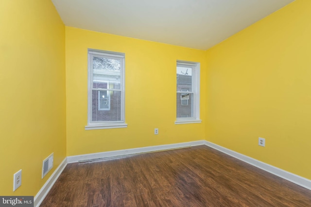 unfurnished room with baseboards, visible vents, and dark wood-type flooring