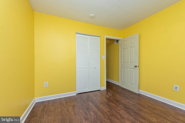 unfurnished bedroom featuring dark wood-type flooring, baseboards, and a closet