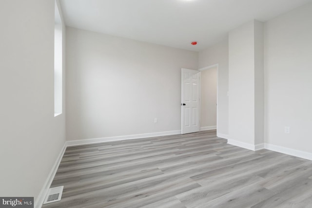 spare room featuring light wood-style floors, baseboards, and visible vents